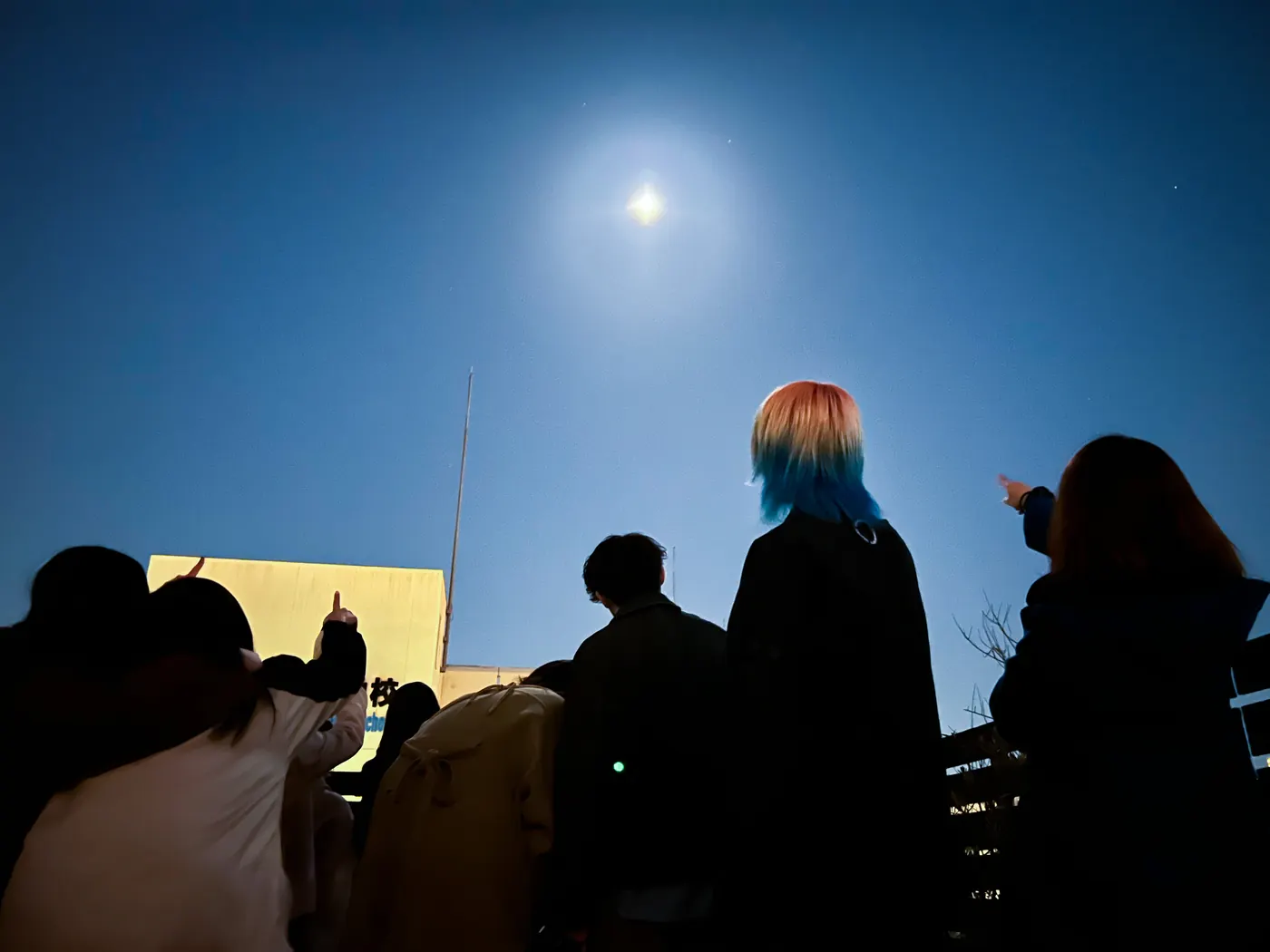 屋上で夜空の月を見上げるお客様